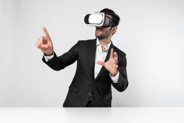 Akıllı yönetici veri analizine işaret ederken VR gözlüğü kullanarak veriye bakıyor. Beyaz yatırımcı takım elbise ve sanal gerçeklik kulaklığı takarken metaevreni birbirine bağlıyor. Yenilik teknolojisi. Sapma.