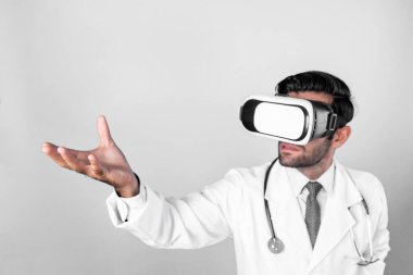 Zeki doktor, kameraya bakıyor ve beyaz arka planda duruyor. Sanal gerçeklik ya da metadünya giyerken tıbbi verileri elinde tutan ve kontrol eden beyaz bir doktor. Yenilik teknolojisi. Sapma.