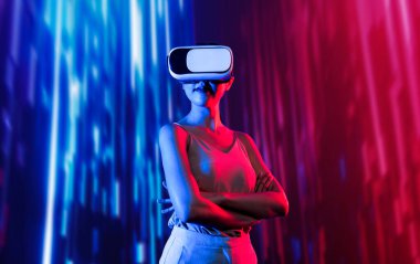 Zeki bir kadın, metaevreni birbirine bağlayan VR kulaklık takan neon ışıklarla çevrili duruyor. Gelecekteki siber uzay topluluğu teknolojisi. Zarif kadın kendinden emin bir şekilde çapraz kol pozu veriyor. Uzağa bak. Halüsinasyon.