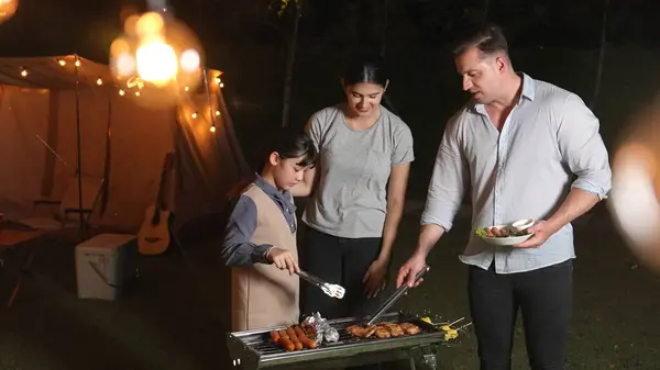 stock image Family celebrate holiday in garden. Father, mother and child grill food for member. Outdoor camping activity to relax with meal and spend time with young generation cross generation gap. Divergence.