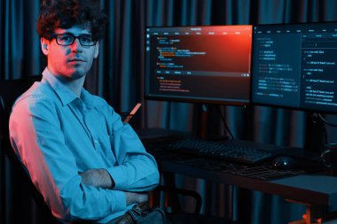 Uygulama ekranı arkaplanındaki kodlama programında gece vakti çevrimiçi yazılım geliştirme bilgisiyle kameraya bakan IT geliştiricisi güncellenmiş yazılım donanımı yaratıyor. Toplayıcı.