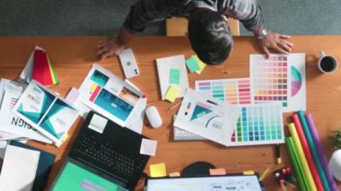 Kulaklıktan müzik dinlerken yetenekli iç dizayn grafiklerinin yukarıdan aşağı havadan görüntüsü. Proje yöneticisi kulaklıkla çalışırken ve rahat şarkılar dinlerken stüdyoda hareket ediyor. Sempozyum.