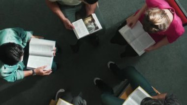 İncil 'i okuyup, kucağında İncil' le daireler çizerek otururken en tepeden aşağı dua manzarası. İnanç, güven ve umut ve sükunetle çalışırken farklı insanların kitaba bakışları. Sempozyum.