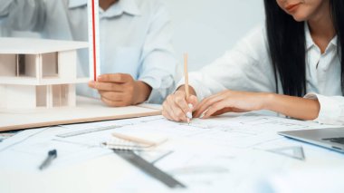 Profesyonel mühendis ev modelini tartartarken, yetenekli tasarımcı da planına yazar. Birlikte çalışmak, işbirliği, işbirliği. Yaratıcı tasarım ve takım çalışması konsepti. - Yakın çekim. Tertemiz.