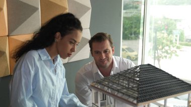 Profesyonel muhtelif mimari mühendis takımı ev modelini kontrol ediyor. Beyaz mühendis ev inşaatını sunarken güzel İspanyol yönetici de ofis tasarımını inceliyor. - Yakın çekim. Yönlendirici.