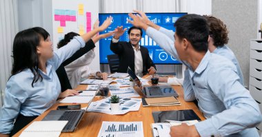 Kutlama jesti ve başarılı takım çalışması yapan bir grup mutlu çoklu etnik iş adamı başarılı satışlar yaptıktan sonra veya toplantı odasında ekranda pozitif finansal veri gösterimi yaptıktan sonra. Habiliment