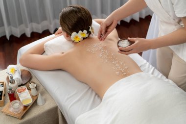 Lüks spa salonlarında sıcak mum ışığında cilt bakımı yaptıran kadın müşteri. Sağlık Spa vücut fırçasında tuz temizleme güzellik tedavisi. Sessiz.