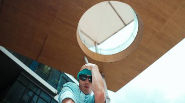 Havalı poz verirken kameraya bakan beyaz tenli yakışıklı hippinin düşük açılı portresi. Serbest stil dansı yaparken şık bir dansçı gülümsemesi. Açık hava sporu 2024. ÇalışmaComment.