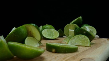 Yakın plan, canlı bir dilim taze kireç kırsal bir ahşap kesme tahtasının üzerinde duruyor. Tazelik ve canlılık yayıyor. Kesme tahtasına konmuş yeşil limon diliminin yarı saydam zarları. Geliştirilebilir.