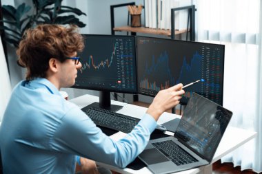 Laptop ve pazar stok grafiğinde dizüstü bilgisayar ve bilgisayar üzerinde çalışan genç tüccarlar modern yurt içi ofislerinde gerçek zamanlı ekranlara yatırım yaparak dinamik döviz kuru yatırım konseptini analiz ediyorlar. Toplayıcı.