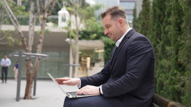 Green City 'de otururken bilgisayarla çalışan iş adamlarının yan görüntüsü. Akıllı yönetici bilgisayar yazma raporunu ve pazarlama stratejisini uzaktan kumandayla iş ekibiyle çalışırken kullanıyor. Urbane.