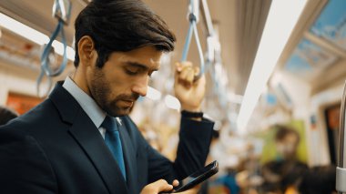 Trende insanlarla çevrili dururken telefona bakan profesyonel bir iş adamı. Kafkas proje yöneticisi e-postaları kontrol ediyor, arka planı bulanık pazarlama stratejisi planlıyor. Sevinçli..