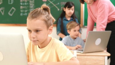 Kafkasyalı çocuk çeşitli öğrenci kodlama mühendisliği programlarıyla çevrili program yazarken programlama sistemine odaklanıyor. Happy öğretmen bilgisayar dersinde dizüstü bilgisayarda çalışan çocuklara destek oluyor. Pedagoji.