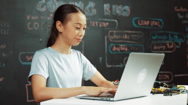 Kara tahtada dizüstü bilgisayar kullanarak akıllı kız programlama sistemi. Lise öğrencisi BTMM teknoloji sınıfında ekrana bakarken mühendislik kodu yazıyor. Yaratıcı eğitim. Öğretim.