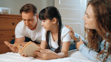 Çocukluk hikayeleri anlatan uyku zamanı, anne ve baba rahat ve rahat yatak odasındaki küçük kızlarına birlikte fantezi kitabı okuyorlar. Modern aile eğlencesi. Eşzamanlama