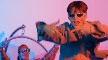 Asyalı sokak dansçısının neon ışıkla pop müziğe geçişine yakın çekim yaparken çeşitli arkadaşlar oturuyor ve performansı destekliyor. Profesyonel sanatçı stüdyoda dans figürleri yapıyor. Mutluluk.