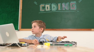 Kameraya karatahta ile bakarken elektronik tahtada çalışan zeki bir öğrenci. Çocuk, kodlama mühendisliği ve yapay zeka kullanarak programlama sistemine hazırlanırken ana tahtayı tamir ediyor. Pedagoji.