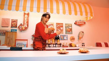 Profesyonel Asyalı restoran işçisi yemek hazırlar ve yemek barının arkasında durur. Kırmızı gömlekli ve kırmızı önlüklü mutlu garson kameraya bakarken serbest stil müziğe geçiyor. Çılgın dans. Mutluluk.