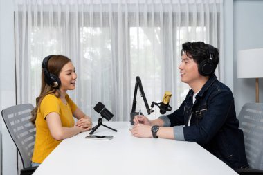 Gülümseyen radyo etkili sunucusu kulaklık takıyor kadın konuşmacı ile röportaj yapıyor sosyal medya internet sitesinden dinleyicilere bilgi paylaşıyor stüdyo kaydında sabah canlı yayın kanalı. İnfobahn.