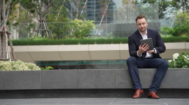 Profesyonel işadamı, pazarlama ekibinin raporlarını okuyarak tablet üzerinde çalışırken parkta oturuyor. Mutlu yönetici artan satışlar ya da Eko City 'de gülümserken başarılı bir proje arıyor. Urbane