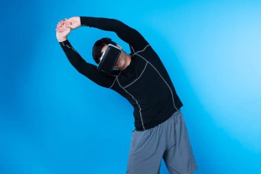 VR kullanan zeki bir oyuncu sağlıklı vücut egzersizi için kollarını uzatarak meta-şehirdeki gelecekteki teknolojik sanal gerçekliğe bağlanan mavi arka plan üzerinde çalışıyor. Entrika.