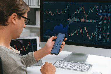 Akıllı borsa yatırımcıları ekranda akıllı telefon ile piyasa borsasını işaret ederek dizüstü bilgisayarın yanı sıra en yüksek dinamik yatırım oranını göstererek, modern işyerindeki veri planlamasına odaklanıyorlar. Bireysel.