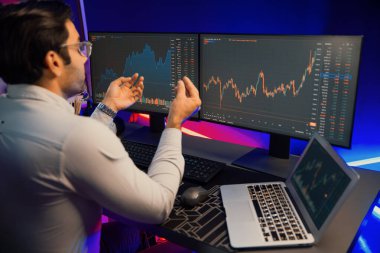 Akıllı tüccar işadamı, karanlık oda gecesinde neon ışıklı ofisteki arama pazarında yüksek kârla ekranda bilgisayar ve bilgisayar üzerinde dinamik borsa yatırımları üzerinde yoğunlaşıyor. Tahmin et..