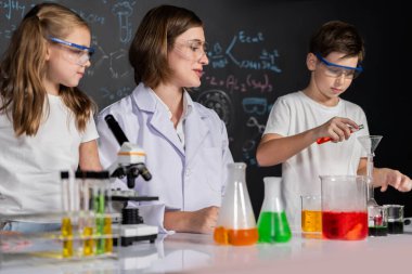 Laboratuvarda çalışan öğretmen, güvenlik gözlüğü takıyor, STEM sınıfında kimya bilimi üzerine deney yapıyor. Öğrenci komedisi tüpte sıvı deneyi yapar. Etkinlik.
