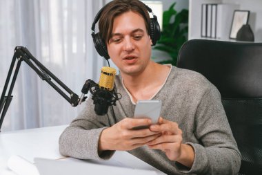 Akıllı yayıncının sunucu kanalı canlı sosyal medya yayını ile akıllı telefon kullanarak dinleyiciyle sohbet ediyor, kulaklık takarak modern ev stüdyosunda video kaydediyor. Bireysel.