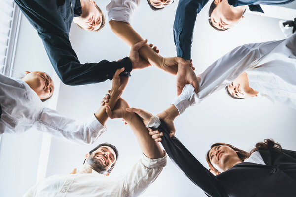 Business team joining hand in circular together symbolize successful group of business partnership and strong collective unity teamwork in diverse culture community workplace. Prudent