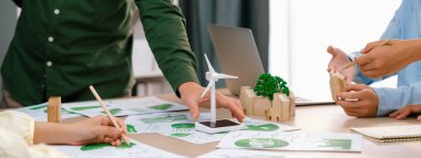 Yenilenebilir enerji ve eko kenti temsil eden ahşap bloğu temsil eden yel değirmeni modeli, çevreci dökümanların dağıtıldığı yeşil iş toplantısı masasına yerleştirildi. Ön manzara. Tanımlama.