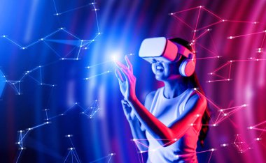 Zeki bir kadın, metaevreni birbirine bağlayan VR kulaklık takan neon ışıklarla çevrili duruyor. Gelecekteki siber uzay topluluğu teknolojisi. Sanal gerçeklik objesini kullanan zarif bir kadın. Halüsinasyon.