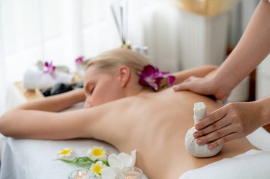 Sıcak bitkisel top spa masaj vücut tedavisi, masör kadın vücuduna nazikçe şifalı bitki torbası bastırıyor. Aromaterapi dinlenme sükuneti ve sükuneti kaplıca salonundaki atmosferi aydınlatıyor. Sessiz.