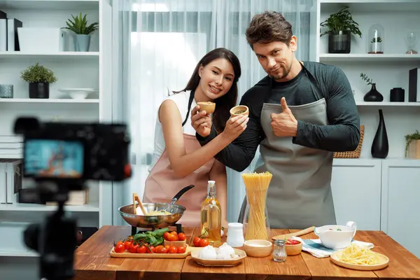 stock image Couple chef influencers on cooking show presenting ingredient of spaghetti, meat, chilli, tomato, garlic and seasoning sauces homemade special recipe recording on camera on live channel. Postulate.