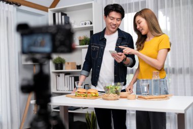 Aşçılar, sosyal medya yemek programı kanalı canlı yayın menü yemeği salatası, kepekli çörek ve video kameradan hamburger kaydı için telefonda yorum okuyorlar. İnfobahn.