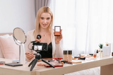 Sosyal medya için güzellik ve kozmetik video içeriği hazırlayan genç bir kadın. Güzellik blogcusu kameraya gülümserken seyircilere ve takipçilere güzellik bakımını gösteriyor. Blithe