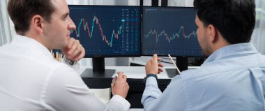Borsa simsarları panorama manzarasında iki ekranla karşılaştırma yaparak, monitörde analiz yaparak borsa borsasını tartışıyorlar. İş yerindeki finansal teknoloji krizi kavramı. Satılabilir.