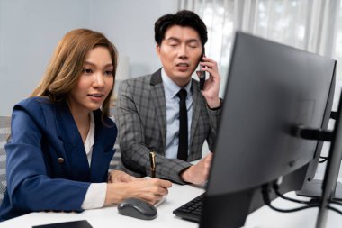 İş ortağıyla cep telefonundan arayan işadamı bilgisayardaki kadın iş arkadaşıyla hisse senedi değer veri tabanını hesaplarken şirket değerini analiz ediyor ya da güncel alım yapıyor. İnfobahn.