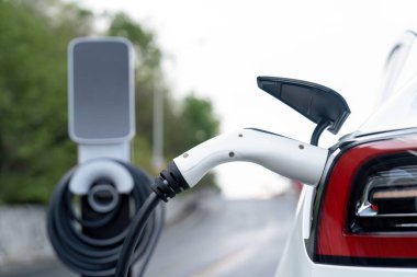 Kapalı EV şarj kolu fişe takıldı veya elektrikli arabaya bağlandı, EV araba aküsünü temiz çevre için sıfır CO2 emisyonu ile alternatif ve sürdürülebilir enerjiyle şarj etti. Kalıcı