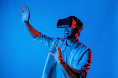 Heyecan verici bir sporcu el hareketi yaparken VR gözlüğü takıyor. Yetenekli genç ayakta duruyor ve teknolojik yenilikleri kullanarak gelecekteki sanal dünya programını veya metaevreni inceliyor. Sapma.
