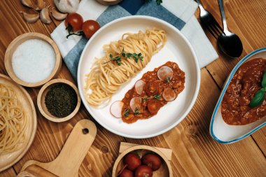 Lezzetli yiyecekler, ev yapımı spagetti, kıymalı domates sosu ve fesleğen fırlatma elementleri, şef masası dekoratif baharatlarla servis ediliyor. Varsayım.