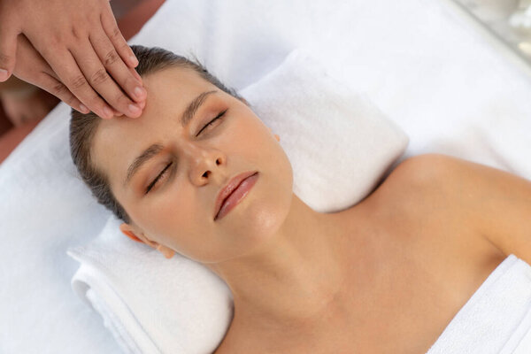 Panorama top view of woman enjoying relaxing anti-stress head massage and pampering facial beauty skin recreation leisure in dayspa modern light ambient at luxury resort or hotel spa salon. Quiescent