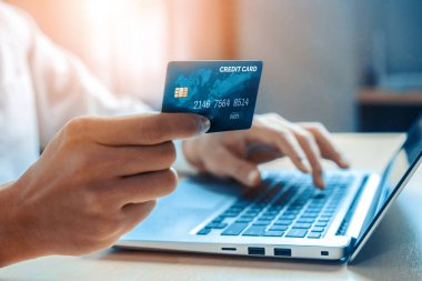 Genç adam, laptop bilgisayar başvurusu ya da web sitesinde online alışveriş yapmak için kredi kartı kullanıyor. E-ticaret ve online alışveriş konsepti. uds