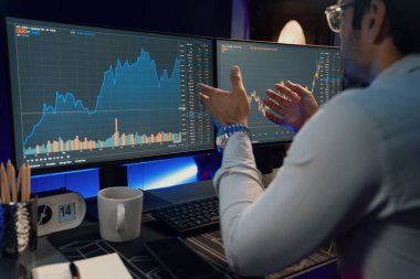 Akıllı tüccar işadamı, karanlık oda gecesinde neon ışıklı ofisteki arama pazarında yüksek kârla ekranda bilgisayar ve bilgisayar üzerinde dinamik borsa yatırımları üzerinde yoğunlaşıyor. Tahmin et..