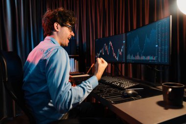 Başarılı genç tüccar, küresel piyasadaki en yüksek kar getiren online veri grafiğini gerçek zamanlı olarak neon ışıklı modern ofiste yükselterek değerli hisse senedi yatırımları elde etti. Toplayıcı.