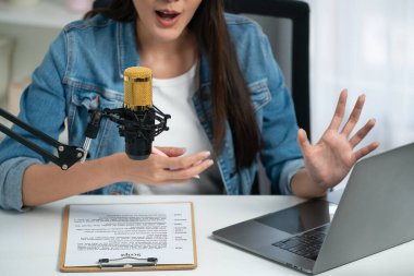 Sosyal medyada kulaklıkla canlı yayın yapan Asyalı sunucu modern stüdyoda yaşam koçluğu veya pazarlama dinleyicilerini selamlıyor. Taktik.