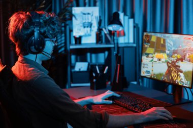 Genç oyun flamasının sunucu kanalı, takım oyuncusu, dijital neon odasında mikrofonlu kulaklık takarak bilgisayar ekranında çoklu oyuncuyla savaş oyunu oynuyor. Toplayıcı.