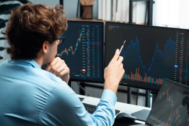 Piyasa stoku grafiği üzerinde çalışan genç profesyonel tüccar ev ofisindeki gerçek zamanlı ekranlara yatırım yaparak önemli döviz kuru kavramları yazarak analiz ediyor. Toplayıcı.