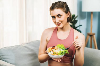 Spor giyimli sağlıklı ve vejetaryen bir kadın bir kase meyve ve sebzeyle. Sağlıklı beslenme ve spor için vejetaryen yaşam tarzı ev konseptinde vücut fiziği.