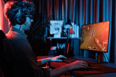 Savaş arenasında çoklu oyunlar takımıyla Moba 'da savaşan genç oyun flamasının sunucu kanalı, neon dijital ışık modern odasındaki arka görüntü ile bilgisayar monitöründe kulaklık takıyor. Toplayıcı.